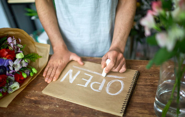 Business owner creating an 'open' sign for their new venture, illustrating the process of filing a DBA for business.